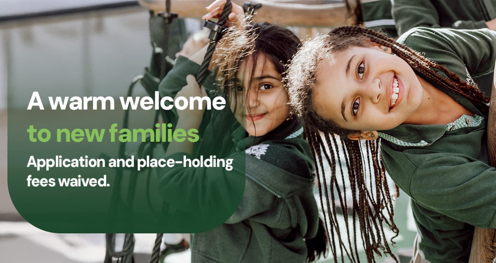 Two smiling schoolgirls beside the line “A warm welcome to new families”